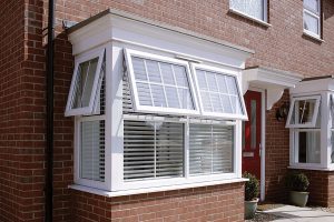 Exterior view of a white uPVC bay window with multiple angled panes. The window design enhances the building's facade, creating a bright and spacious interior while providing a clear view of the outside.